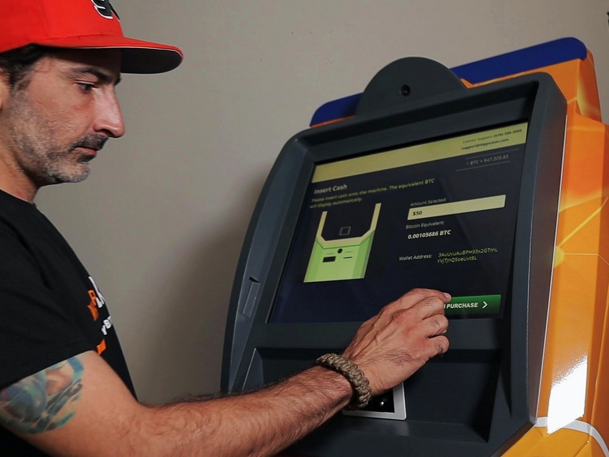 Are Crypto ATMs Illegal? Here is Why the UK is Banning Bitcoin Crypto ATMs. Man using bitcoin ATM machine.